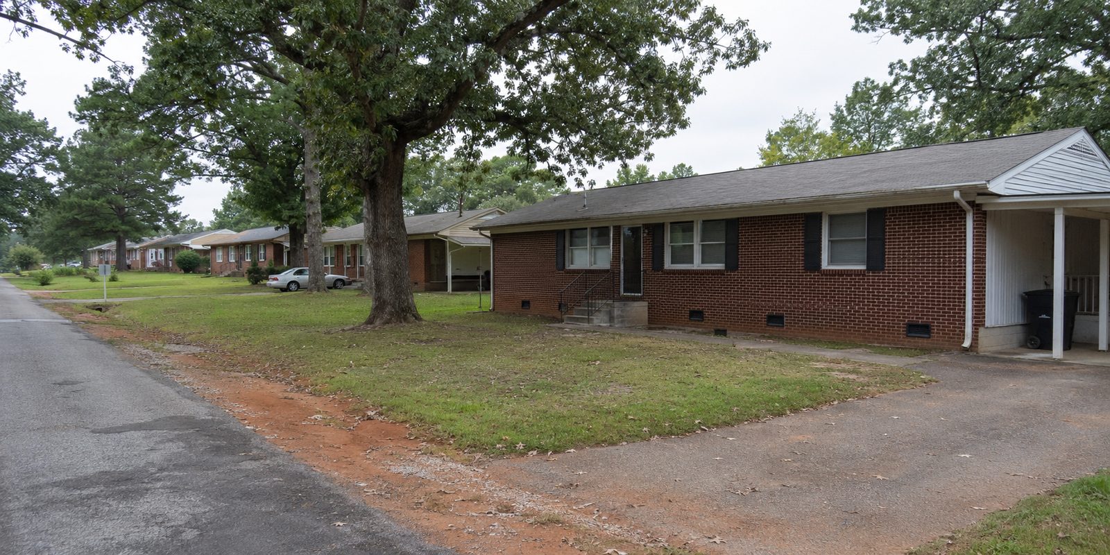Brick ranch houses with carports and foundation vents on a tree-lined Huntsville street